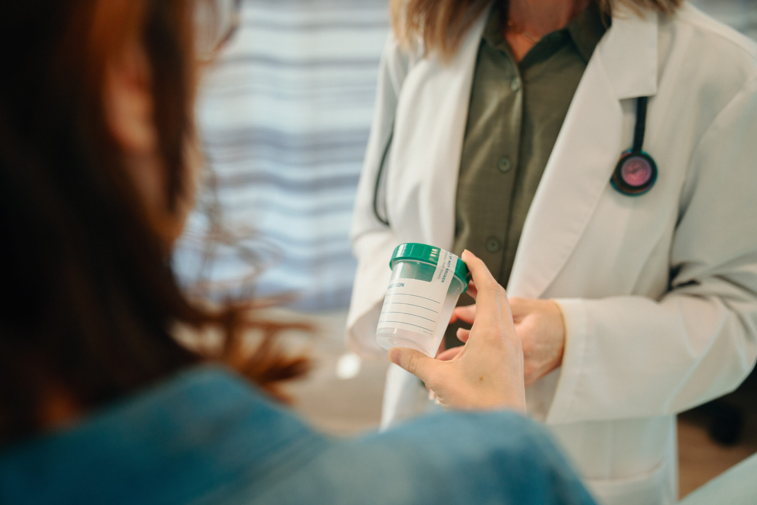 Patient holding urine sample cup